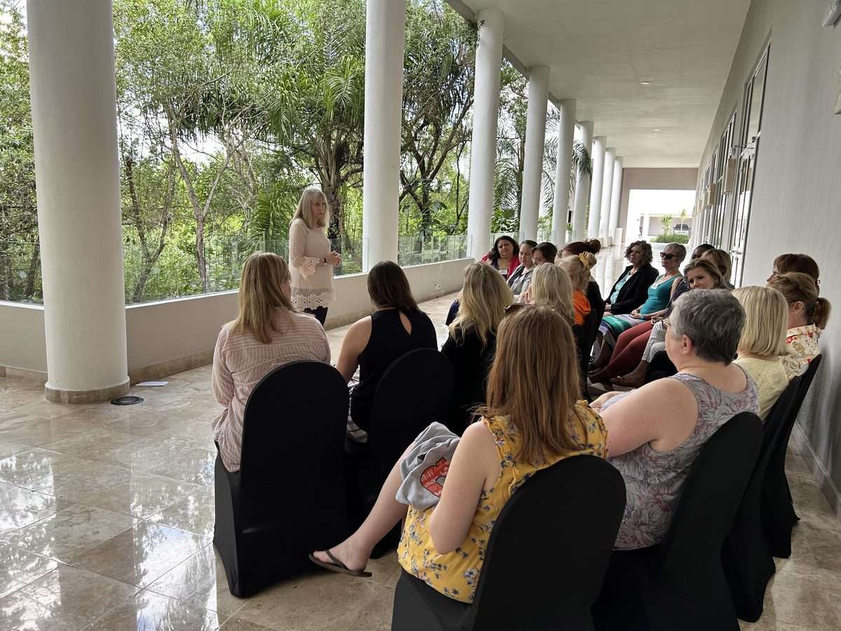 Clinicians seated for an open-air workshop session at Leading Edge Cancun, tropical greenery beyond the columns